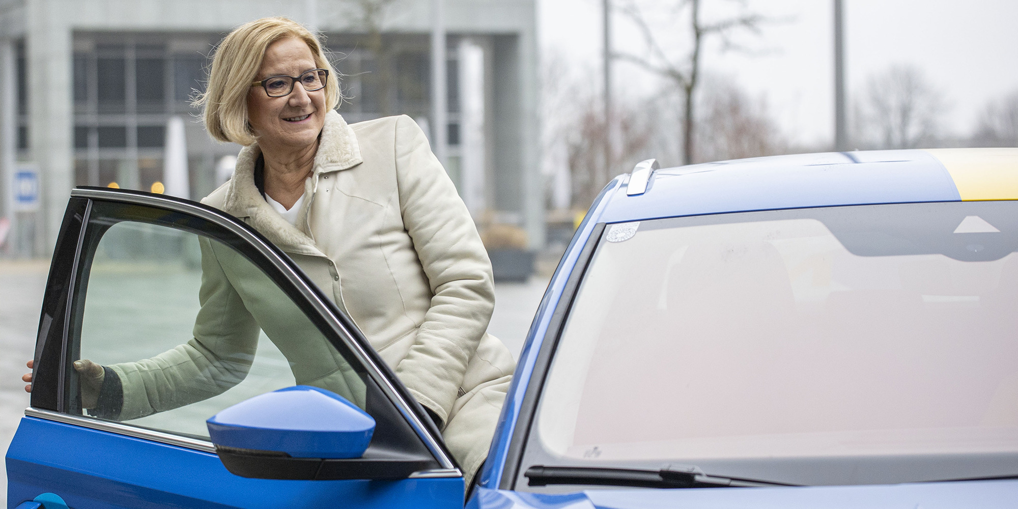 Johanna Mikl-Leitner steigt in ein blaues Auto ein.